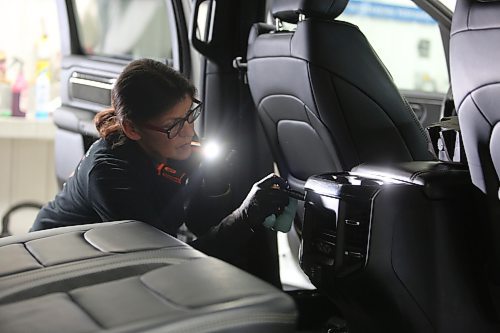 Shawn Simpson, detailer with Resurrection Auto Detailing Tint and Protection uses a flashlight while cleaning a truck's interior at the company's shop in Brandon on Thursday. (Michele McDougall/The Brandon Sun) 
