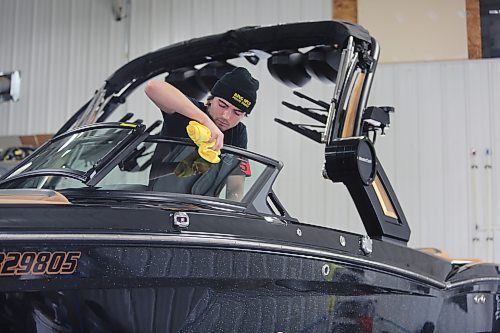 Zach Heidie, a window tinter with Resurrection Auto Detailing Tint and Protection with the last finishing touches on a Mastercraft wakeboarding boat at the company's shop in Brandon on Thursday. (Michele McDougall/The Brandon Sun) 
