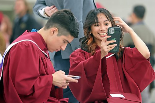 Assiniboine Community College student Jasmin Jade Jimeno chats with her mother, who is back home in the Phillippines, via video phone while dressed in her graduation gown on Friday afternoon, while her friend and fellow ACC grad Javier Pena Garcia taps out a message. Jimeno graduated yesterday from ACC's Food Processing program with distinction, and hopes to land a job with Maple Leaf Foods here in Brandon doing quality control. (Matt Goerzen/The Brandon Sun)