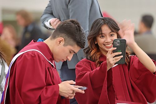 Assiniboine Community College student Jasmin Jade Jimeno waves to her mother back home in the Phillippines via video phone while dressed in her graduation gown on Friday afternoon, while her friend and fellow ACC grad Javier Pena Garcia taps out a message. Jimeno graduated yesterday from ACC's Food Processing program with distinction, and hopes to land a job with Maple Leaf Foods here in Brandon doing quality control. (Matt Goerzen/The Brandon Sun)