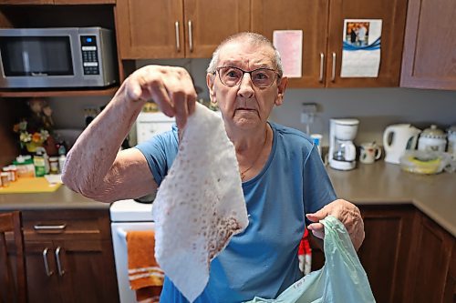 Donnalee Cotter holds up a dusting cloth covered in white and pink material after sweeping her apartment at Princess Towers. She said despite requesting assistance for half a year, it's been difficult to get Manitoba Housing to assist her with frequent white paint flecks that collect all over her belongings and a thermostat that keeps her bedroom at 30 C or warmer. (Colin Slark/The Brandon Sun)