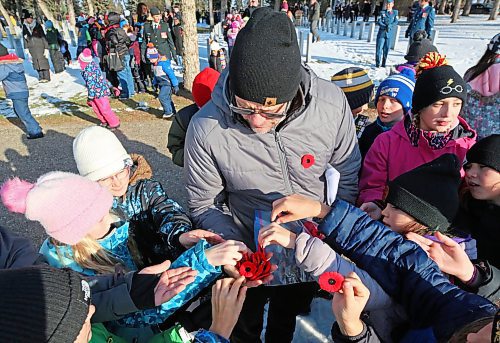 Greg Sylvestre, a Grade 5 teacher at École Harrison, hands out poppies to his students that will be placed at the graves of Canadian Forces members following the No Stone Left Alone ceremony at the Brandon Municipal Cemetery on Friday morning. See story and more photos on Page A8. (Matt Goerzen/The Brandon Sun)