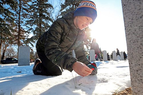 Grade 7 Harrison School student Taven Adema places a poppy on the grave of a Canadian Forces soldier during the No Stone Left Alone ceremony. (Matt Goerzen/The Brandon Sun)