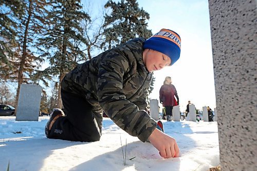 Grade 7 Harrison School student Taven Adema places a poppy on the grave of a Canadian Forces soldier during the No Stone Left Alone ceremony at the Brandon Municipal Cemetery on Friday morning. (Matt Goerzen/The Brandon Sun)