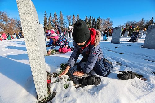 Grade 1 Harrison School student Jackl Kellington places a poppy on the grave of a Canadian Forces soldier during the No Stone Left Alone ceremony at the Brandon Municipal Cemetery on Friday morning. (Matt Goerzen/The Brandon Sun)