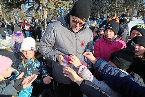 Greg Sylvestre, a Grade 5 teacher at cole Harrison, hands out poppies to his students that will be placed at the graves of Canadian Forces members following the No Stone Left Alone ceremony at the Brandon Municipal Cemetery on Friday morning. (Matt Goerzen/The Brandon Sun)