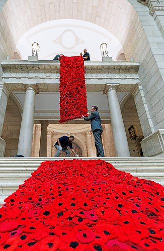 MIKE DEAL / WINNIPEG FREE PRESS
Manitoba Legislative building maintenance staff, Tesfay Fanta (bottom left) and Brad Robertson (bottom right), Manitoba&#x2019;s Chief of Protocol, reach up to catch a section of the Poppy Blanket, Monday morning.
First unveiled in November of 2019 the Poppy Blanket is an 85 foot long collection of over 8000 handmade poppies and thousands of dedicated ribbons. It was made in less than a year between 2018 and 2019 by the Handmade Winnipeg Facebook group community.
231106 - Monday, November 06, 2023.