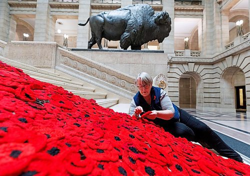MIKE DEAL / WINNIPEG FREE PRESS
Susan Wakeman, one of the volunteers that help maintain the Poppy Blanket, reattaches one of the handmade poppies to the blanket on the Grand Staircase Monday morning.
First unveiled in November of 2019 the Poppy Blanket is an 85 foot long collection of over 8000 handmade poppies and thousands of dedicated ribbons. It was made in less than a year between 2018 and 2019 by the Handmade Winnipeg Facebook group community.
231106 - Monday, November 06, 2023.