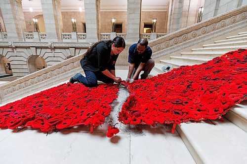 MIKE DEAL / WINNIPEG FREE PRESS
The Poppy Blanket creator, Sheila Lee Restall (left), and Tesfay Fanta (right) with the Manitoba Legislative building maintenance staff, attach the two sections of the Poppy Blanket, Monday morning.
First unveiled in November of 2019 the Poppy Blanket is an 85 foot long collection of over 8000 handmade poppies and thousands of dedicated ribbons. It was made in less than a year between 2018 and 2019 by the Handmade Winnipeg Facebook group community.
231106 - Monday, November 06, 2023.