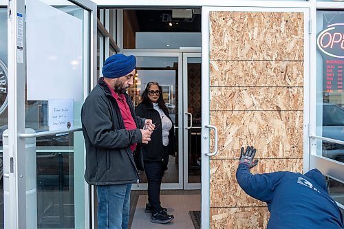 BROOK JONES / WINNIPEG FREE PRESS
The Coffee Culture Caf&#xe9; and Eatery at 2864 Pembina Highway in Winnipeg, Man., was broken into Sunday, Nov. 5, 2023. PIctured: Co-owners Paramjeet Mehendiratta (left) and his wife Sandeep Mehendiratta watch as Curtis Talbot (right) from Border Glass &amp; Aluminum takes off the temporary sheet of wood covering the broken doorlight.