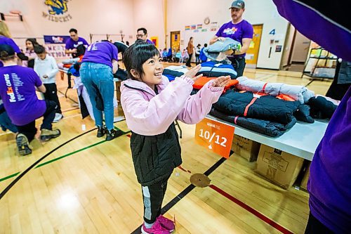 MIKAELA MACKENZIE / WINNIPEG FREE PRESS

FedEx Cares volunteer Christine Zerdin helps eight-year-old Juvana Lagansua try on a coat at Wellington School on Friday, Nov. 10, 2023. Operation Warm (a national non-profit that manufactures brand-new, high-quality coats and shoes for children in need) provided more than 300 new winter coats to the school. Standup.
Winnipeg Free Press 2023.