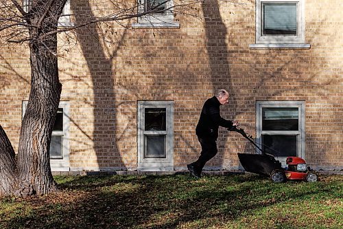 MIKE DEAL / WINNIPEG FREE PRESS
Patrick DeJong, caretaker for the Grandview Apartments, mows the lawn to mulch the leaves that fell after the first snowfall that occurred a few weeks ago. 
231114 - Tuesday, November 14, 2023.