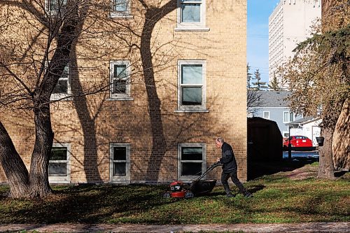 MIKE DEAL / WINNIPEG FREE PRESS
Patrick DeJong, caretaker for the Grandview Apartments, mows the lawn to mulch the leaves that fell after the first snowfall that occurred a few weeks ago. 
231114 - Tuesday, November 14, 2023.