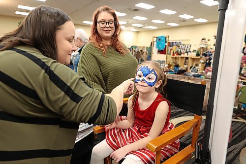 L-R: Lavender Blue Henna & Face Painting owner Stephanie Ritchot making Sonic design on Liliana Larocque-Shurb, 5, while her mum, Taylor Shurb, watches at the Christmas Market on Saturday. Photos: (Abiola Odutola/The Brandon Sun)