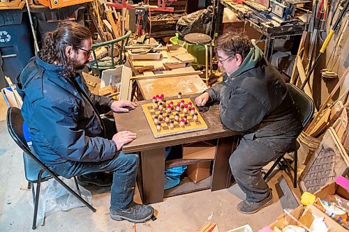 BROOK JONES / WINNIPEG FREE PRESS
Sixty-seven-year-old Bill Gidzak and his son 42-year-old son Nick run a woodworking shop called Artisanal Firewood. The father-and-son team turn out a variety of products, especially Christmas theme decorations and toys for kids. Pictured: Nick (left) and his father Bill play a game of checkers on a board and with pieces they handmade. The board is made of oak wood and the pieces are made of maple wood. The duo were pictured woodworking inside Bill's garage at his home in Winnipeg, Man., Wednesday, Nov. 22, 2023.