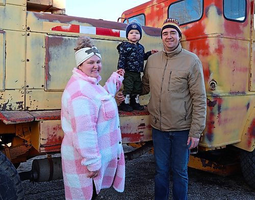Harley Lumb with his wife Hope and their 16-month-old son Axle, stand in front of their yellow 1957 Sicard Snowmaster Senior snow blower truck, west of Brandon. (Michele McDougall/The Brandon Sun)