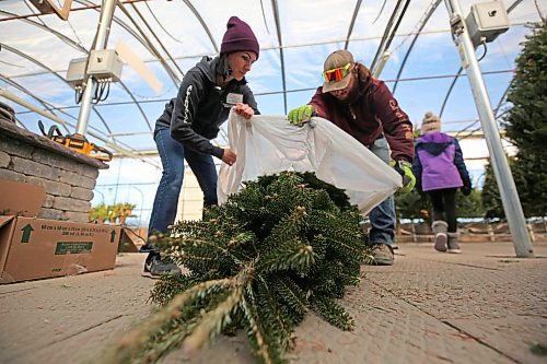 Greenhouse production managers Kerry Van Mackelbergh (left) and Cole Hunt bag up a balsam fir Christmas tree at the Alternative Landscaping Garden Centre on Friday morning. The company is expecting sales of Christmas trees to jump this weekend in the lead-up to the coming holiday season, but they warn that their supply of trees is less than previous years. See story on Page A3. (Matt Goerzen/The Brandon Sun)