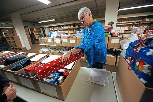 Linda Gillis, the head gift guru for the Brandon-Westman Christmas Cheer Board takes a moment on Friday afternoon to consider gift size relative to that of the Christmas hamper box while readying hampers for the start of deliveries next week. (Matt Goerzen/The Brandon Sun)