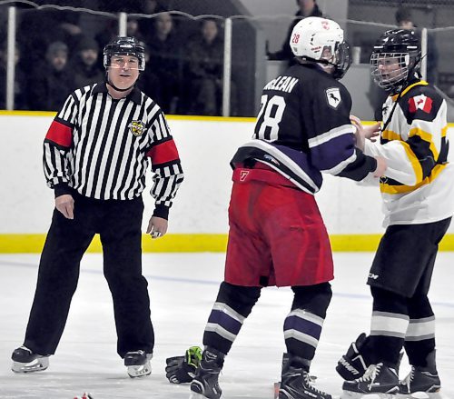 Referee Brad LaRocque, a former B battery player before retiring from 1RCHA, watches as A "The Queen's" battery Lt. Nash McLean wraps up B battery commander major Craig Kelsey during the traditional opening faceoff "fight" during Monday morning's Kingston Cup game at CFB Shilo's Gunner Arena. Lt McLean scored twice to pace his team to an 11-3 victory.
(Photo Jules Xavier/The Brandon Sun)