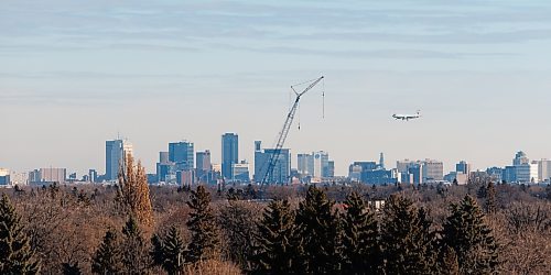 MIKE DEAL / WINNIPEG FREE PRESS
An Air Canada plane heads in for a landing about to fly past a crane which is set up at 215 Sinawik Bay where construction of a new condo building that will open in 2024 as part of the St. James Kiwanis Village, a seniors housing project, with the Winnipeg skyline in the distance Wednesday morning.
231129 - Wednesday, November 29, 2023.