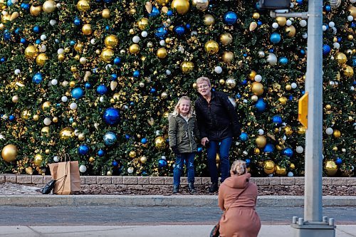 MIKE DEAL / WINNIPEG FREE PRESS
Carly Boklaschuk takes a photo of her daughter Lennyn, 6, and her mother, Debbie Kaminsky, in front of the Christmas tree at City Hall while on their way to see RMTC&#x2019;s The Sound of Music, Wednesday afternoon.
231206 - Wednesday, December 06, 2023.