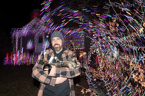 07122023
Patrick Stewart and his cat Ezra outside their brightly decorated and lit-up home at 522 22nd Street in Brandon on Thursday evening. Stewart and his family are asking for donations from visitors to the light show for Paws Crossed Animal Rescue.
(Tim Smith/The Brandon Sun)