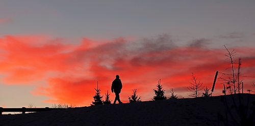 A pedestrian walking along the pathway at the Daly Overpass on 18th Street is silhouetted against the clouds illuminated by the setting sun on a mild Wednesday afternoon. (Tim Smith/The Brandon Sun)