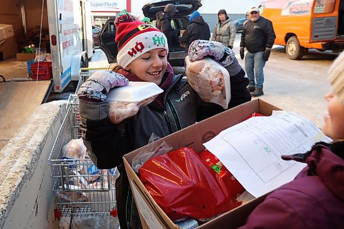 Sofi Harvey loads chickens into Christmas hampers while volunteering at the Brandon & Westman Christmas Cheer Registry along with other grade 7-8 students from Oak Lake Community School on Thursday. Volunteers fanned out across Westman on Wednesday and Thursday to deliver hampers. See story on Page A2. (Tim Smith/The Brandon Sun)