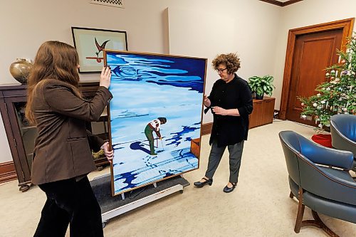 MIKE DEAL / WINNIPEG FREE PRESS
Amy Karlinsky (right), Visual Arts Consultant, Sport Culture Heritage and Tourism, and a staff member hang a painting by Ilona Stanley, titled &#x201c;Winter Wind,&#x201d; in Minister of Health, Seniors and Long-Term Care, Uzoma Asagwara&#x2019;s office.
231207 - Thursday, December 07, 2023.