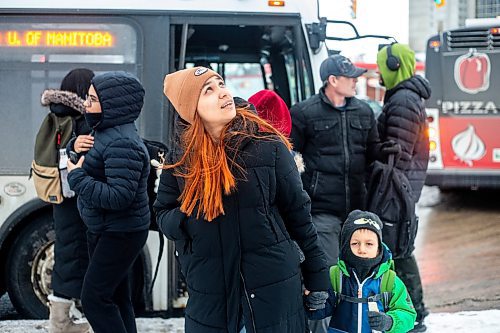 MIKAELA MACKENZIE / WINNIPEG FREE PRESS
	
Venera Sorkina looks up to the estimated arrival time board for the second bus on their way home from Mosaic's English language class on Monday, Dec. 11, 2023. For Malak story.
Winnipeg Free Press 2023