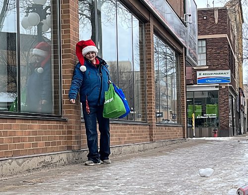 Brandon's Katherine Davis hugs a building, avoiding the ice-covered sidewalk along Rosser Ave., on Tuesday afternoon. (Michele McDougall/The Brandon Sun)