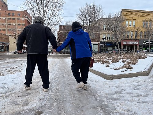 An unidentified couple hold onto each other for support on an icy sidewalk on Ninth Street in downtown Brandon on Tuesday afternoon. (Michele McDougall/The Brandon Sun)