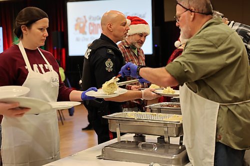 Volunteers line up to get plates filled as the free Christmas dinner was in full swing at noon on Monday. (Geena Mortfield/The Brandon Sun)