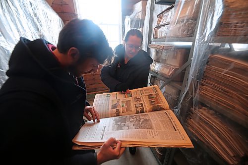 Keith Waterfield (left) and Aly Wowchuk (right) pore through an old edition of the Brandon Sun in the newspaper archives' new temporary home at the Commonwealth Air Training Plan Museum. (Colin Slark/The Brandon Sun)