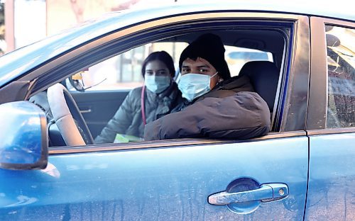 Isaac Lotis is behind the wheel with Manuela Osyro in the passenger seat, while wearing masks to protect others as they recover from a respiratory viral illness, in downtown Brandon on Thursday. (Michele McDougall/The Brandon Sun)