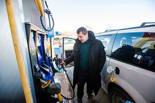 MIKAELA MACKENZIE / WINNIPEG FREE PRESS
	
Egor (no last name given) fills up his tank at the Polo Park Mobil gas station on Friday, Dec. 29, 2023. The gas tax will be paused on Jan. 1st, which should further reduce gas prices. For Danielle story.
Winnipeg Free Press 2023