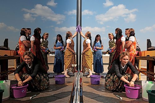 Young women in colourful dresses are reflected in the glass of CanAmerican Corrugating Co. While washing the windows of the manufacturing business at CanAm Hutterite Colony east of Minto, Manitoba on a warm late August day.

Tim Smith for the Brandon Sun