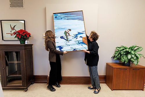 MIKE DEAL / WINNIPEG FREE PRESS
Amy Karlinsky (right), Visual Arts Consultant, Sport Culture Heritage and Tourism, and a staff member hang a painting by Ilona Stanley, titled &#x201c;Winter Wind,&#x201d; in Minister of Health, Seniors and Long-Term Care, Uzoma Asagwara&#x2019;s office.
231207 - Thursday, December 07, 2023.