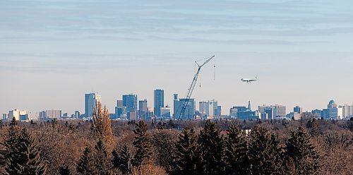 MIKE DEAL / WINNIPEG FREE PRESS
An Air Canada plane heads in for a landing about to fly past a crane which is set up at 215 Sinawik Bay where construction of a new building that will open in 2024 as part of the St. James Kiwanis Village, a seniors housing project, with the Winnipeg skyline in the distance Wednesday morning.
231129 - Wednesday, November 29, 2023.