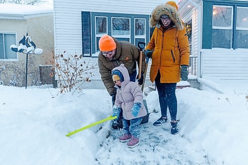 MIKE DEAL / WINNIPEG FREE PRESS
David and Laura Noel-Romas clear snow off of their front walk on Sherburn Street, with daughter, Josephine, 2, Thursday morning.
240111 - Thursday, January 11, 2024.