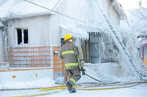 BROOK JONES / WINNIPEG FREE PRESS
Firefighters with Winnipeg Fire Paramedic Service responded to a fire in a two-and-a-half-storey multi-family house in the 100 block of Rex Avenue in Winnipeg, Man., around 11:20 a.m., Sunday, Jan. 14, 2024. By 3:30 p.m. crews were clearing the scene as the house, which was seriously damaged by fire, continued to smolder. Pictured: A firefighter carries a fire hose.