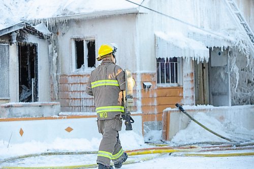 BROOK JONES / WINNIPEG FREE PRESS
Firefighters with Winnipeg Fire Paramedic Service responded to a fire in a two-and-a-half-storey multi-family house in the 100 block of Rex Avenue in Winnipeg, Man., around 11:20 a.m., Sunday, Jan. 14, 2024. By 3:30 p.m. crews were clearing the scene as the house, which was seriously damaged by fire, continued to smolder. Pictured: A firefighter carries a fire hose.
