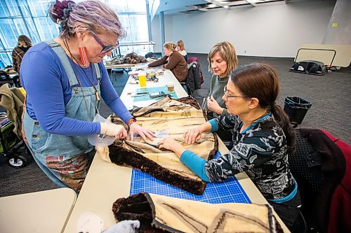 MIKAELA MACKENZIE / WINNIPEG FREE PRESS
	
Leather artist Sheila Cailleau (left) shows Beverley Findlay (right) and Tracey Miller how to cut pattern pieces out of a fur coat during a mitt making workshop at the Millennium Library ideaMILL on Thursday, Jan. 18, 2024. The mitts, which are made using re-purposed leather and fur coats, will be donated to an agency for community members in need.  Standup.
Winnipeg Free Press 2024