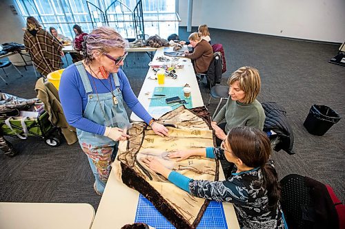 MIKAELA MACKENZIE / WINNIPEG FREE PRESS
	
Leather artist Sheila Cailleau (left) shows Beverley Findlay (right) and Tracey Miller how to cut pattern pieces out of a fur coat during a mitt making workshop at the Millennium Library ideaMILL on Thursday, Jan. 18, 2024. The mitts, which are made using re-purposed leather and fur coats, will be donated to an agency for community members in need.  Standup.
Winnipeg Free Press 2024