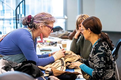 MIKAELA MACKENZIE / WINNIPEG FREE PRESS
	
Leather artist Sheila Cailleau (left) shows Beverley Findlay (right) and Tracey Miller how to take the sleeves off of a fur coat during a mitt making workshop at the Millennium Library ideaMILL on Thursday, Jan. 18, 2024. The mitts, which are made using re-purposed leather and fur coats, will be donated to an agency for community members in need.  Standup.
Winnipeg Free Press 2024