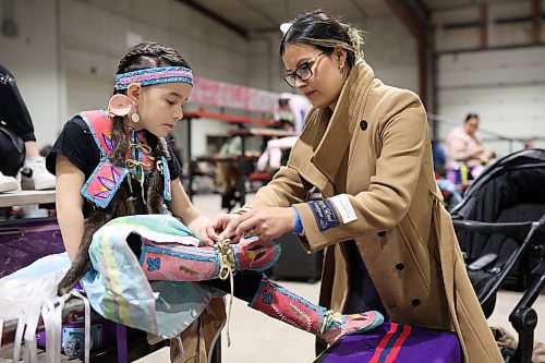 26012024
Prairie Bear of Peguis First Nation helps her daughter Sophia, six, get dressed in her fancy shawl regalia at the Dakota Nation Winterfest Powwow at the Keystone Centre on Friday evening. The weekend-long Winterfest includes square dancing, Moccasin games, basketball, volleyball and a variety of other events.
(Tim Smith/The Brandon Sun)
