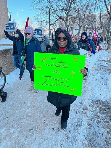 Titi Tijani, president of African Communities of Manitoba, holds a sign during the march.  (Gabrielle Piché / Winnipeg Free Press)