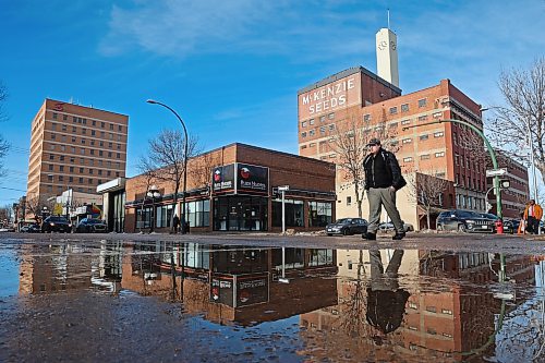 31012024
A pedestrian crossing Rosser Avenue at 9th Street in downtown Brandon is reflected in a puddle of melted snow on an unseasonably warm Wednesday. 
(Tim Smith/The Brandon Sun)