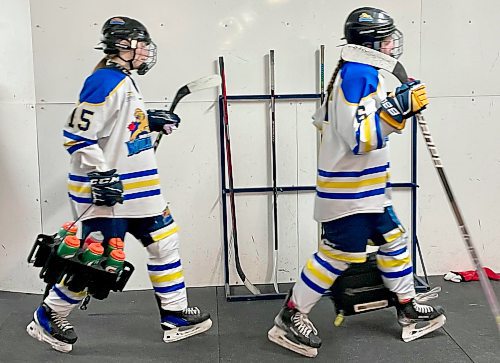 It's time to celebrate the end of the 2023-24 regular season as Westman Wildcats rookies Ivy Perkin (15) and Devyn Moncur (6) carry extra sticks and water bottles to their dressing room following a 3-1 win over the Winnipeg Avros in Hartney. (Jules Xavier/The Brandon Sun)