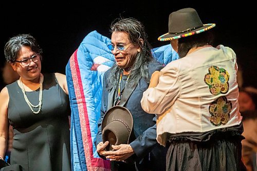 BROOK JONES / WINNIPEG FREE PRESS
Ernest Monias , who is also known as &quot;Elvis of the North&quot; and &quot;King of the North,&quot; is a country music rocker from Pimicikamak Cree Nation (Cross Lake). Pictured: Life-givers Pimicikamak Cree First Nation (Cross Lake) Coun. Brenda Frogg (left) and Assembly of Manitoba Chiefs Grand Chief Cathy Merrick (right) wrap a star-blanket around Monias (middle) during an honouring ceremony in celebration of his 75th birthday at the Burton Cummings Theatre in Winnipeg, Man., Sunday, Feb. 18, 2024. Monias, who has been performing for 60 years, was inducted into the Manitoba Aboriginal Music Hall of Fame in 2005.
